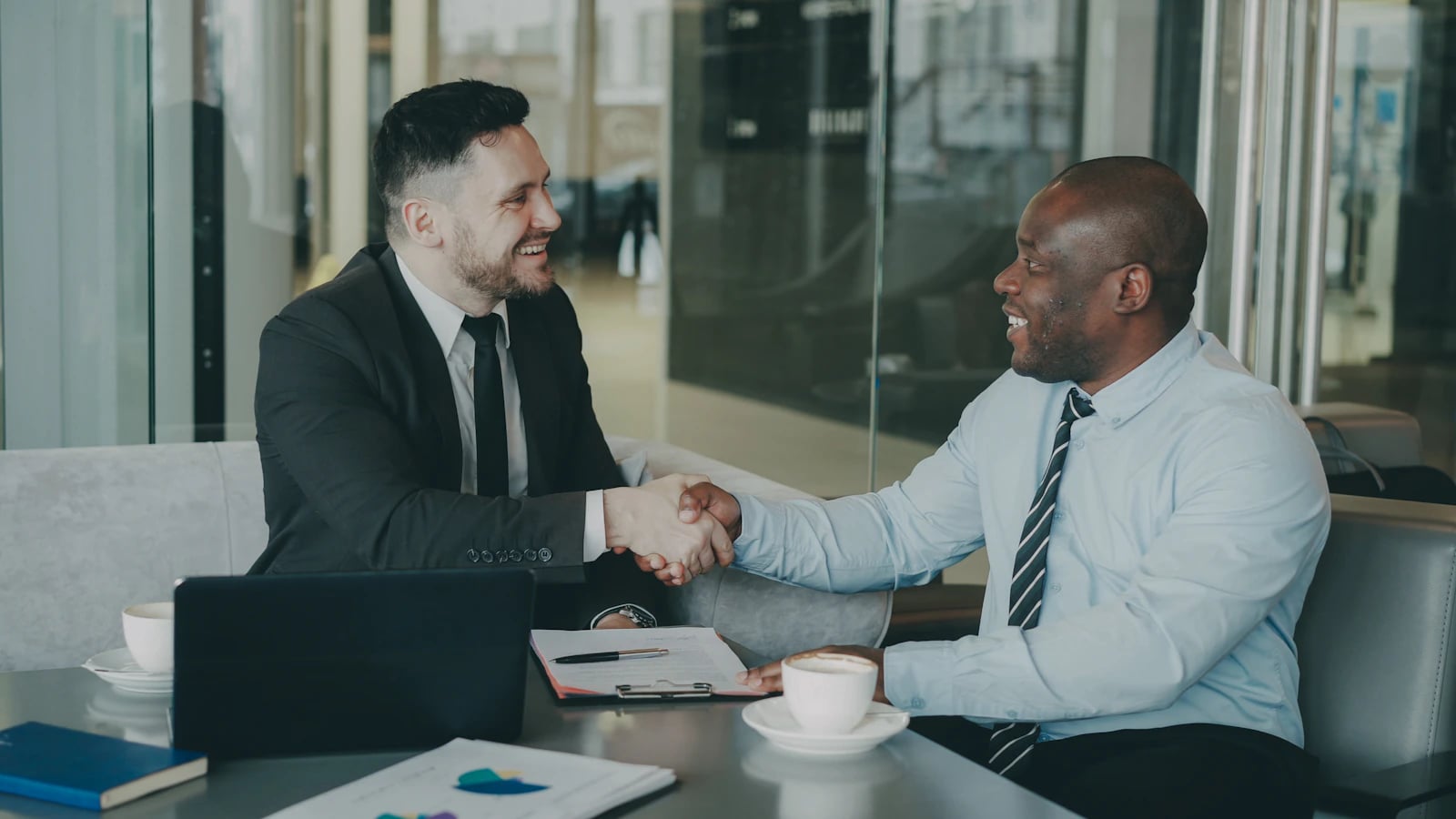 Two businesspeople shaking hands across a table