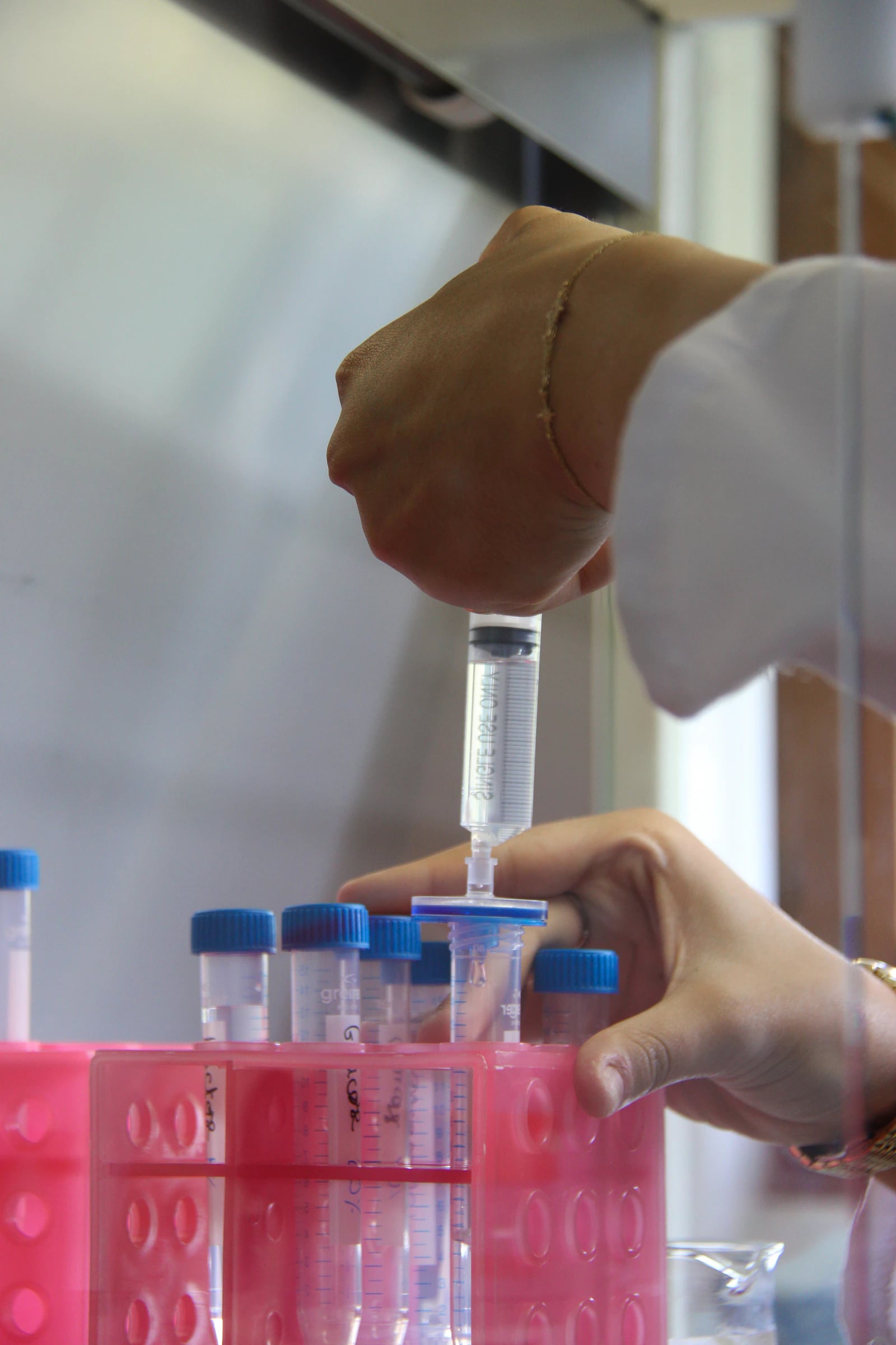 A laboratory technician handling liquid under a filter hood