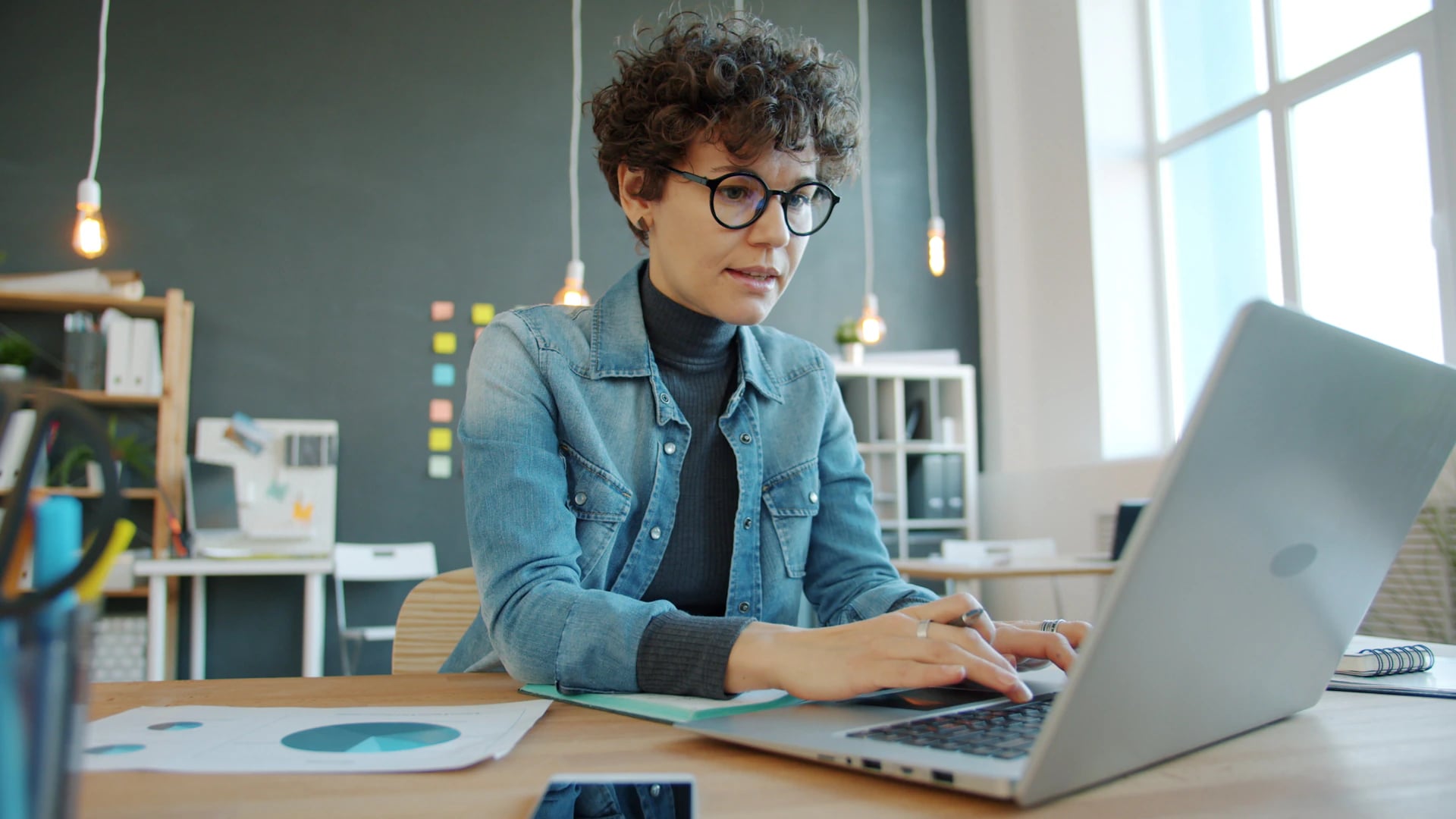 A woman working on a laptop in an office